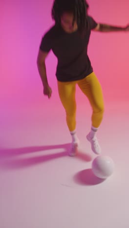 Vertical-Video-Studio-Shot-Of-Female-Footballer-Wearing-Sports-Clothing-Controlling-Ball-With-Feet